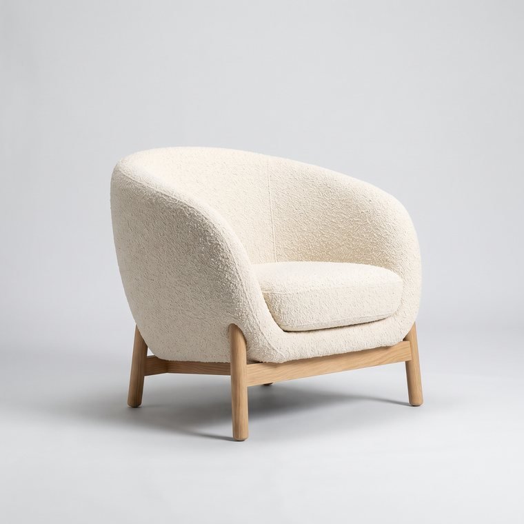 A cream boucle tub chair on a light oak base
